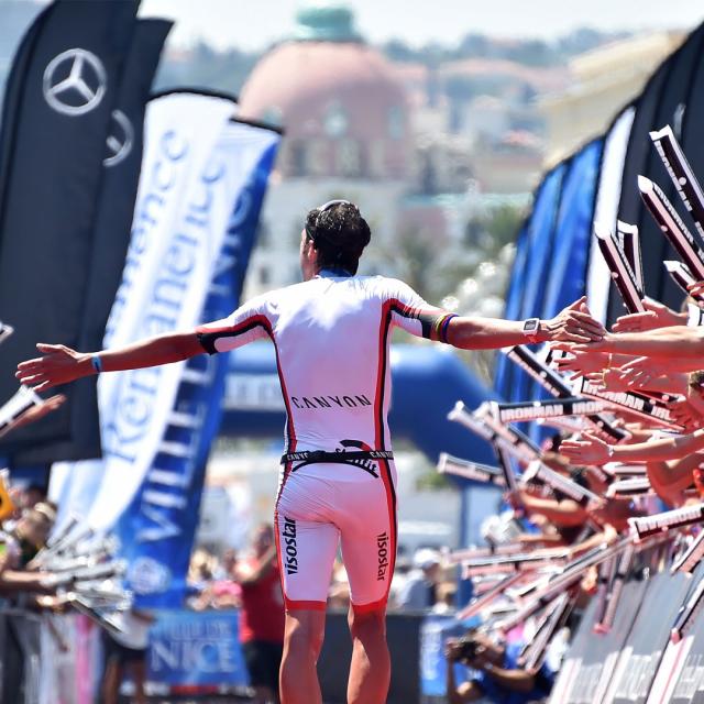 Triathlète franchissant la ligne d'arrivée d'un Ironman sous les acclamations du public